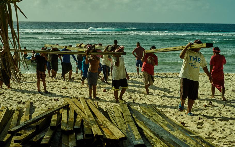 Villagers from Fais Island in the Federated States of Micronesia carry lumber to the beach Dec. 8, 2015. The villagers have no vehicles and the shore is too shallow for ships to moor, so they hand carry incoming supplies from an anchored ship to their single engine fishing boats onto the beach and into the villlage.
