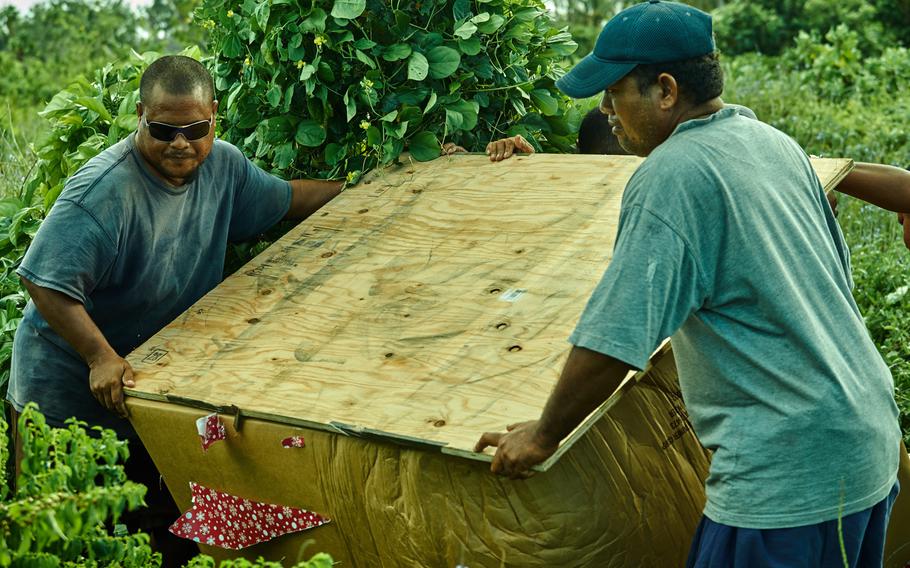 Men from Fais in the Federated States of Micronesia recover an airdropped box somewhere in the middle of their island Dec. 8, 2015. Airmen from the 374th Airlift Wing of Yokota Air Base, Japan, airdropped two boxes with approximately 800 pounds of humanitarian supplies and Christmas presents as part of Operation Christmas Drop.  