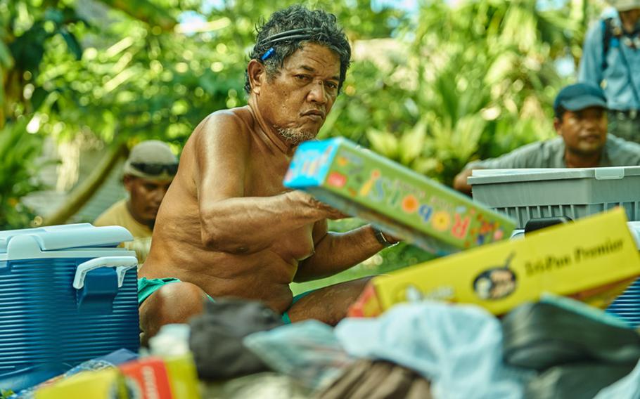 Chief Louis Mangtau, the chief of Fais Island in the Federated States of Micronesia, sorts through the two boxes of humanitarian aid and Christmas presents airdropped onto the island by a C-130 Hercules from Yokota Air Base, Japan Dec. 8, 2015. Once the chief seperates the 800-pounds of goods into three piles for each of the three villages on his island, the villagers will move the items to their respective villages for equal distribution amongst the families.