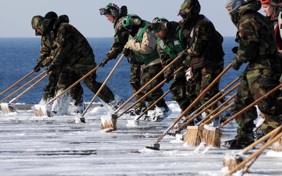 Sailors scrub the flight deck aboard the aircraft carrier USS Ronald Reagan following a countermeasure wash down to decontaminate the flight deck while the ship is operating off the coast of Japan on March 23, 2011. The Reagan, along with 15 other ships that took part in the relief effort, still have some radiation contamination more than five years later, the Navy says.