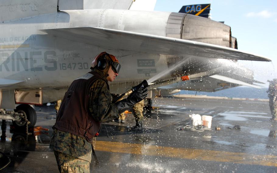 A U.S. Marine sprays the surface of an F/A-18C Hornet aboard the aircraft carrier USS Ronald Reagan during a countermeasure wash down on the flight deck in March 2011. The Reagan, along with 15 other ships that took part in the relief effort, still have some radiation contamination more than five years later, the Navy says. Sailors aboard the ships, however, are not in any danger.