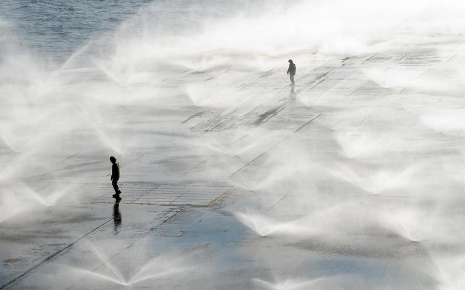 Sailors aboard the aircraft carrier USS Ronald Reagan monitor countermeasure wash down system sprinklers on the flight deck. Sailors scrubbed the external surfaces on the flight deck and island superstructure to remove potential radiation contamination. Ronald Reagan is operating off the coast of Japan providing humanitarian assistance as directed in support of Operation Tomodachi.