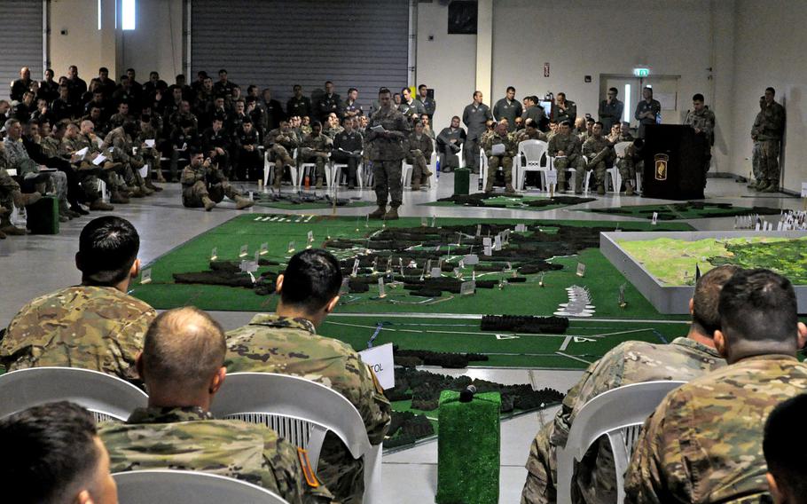 Soldiers and airmen listen to a rehearsal briefing conducted on Saturday, April 9, 2016, at Aviano Air Base, Italy. Dozens of participants detailed their parts in the  Saber Junction exercise with the help of scale models  of the jump zone.