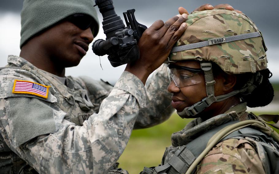 Spc. Christopher McDowell, left, helps Sgt. Chasidy Tenison attach night-vision goggles to her helmet during the 21st Theater Sustainment Command Best Warrior Competition in Baumholder, Germany, on Monday, May 23, 2016.