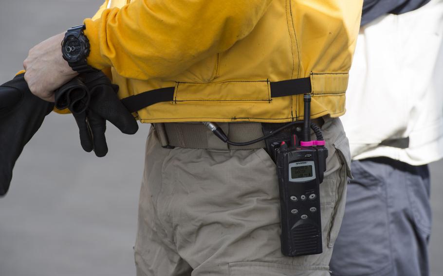 A member of the flight deck crew for the aircraft carrier USS Harry S. Truman has a pink ''Tru Clip'' on his handheld radio to ensure the clasp attachment doesn't crack or break.