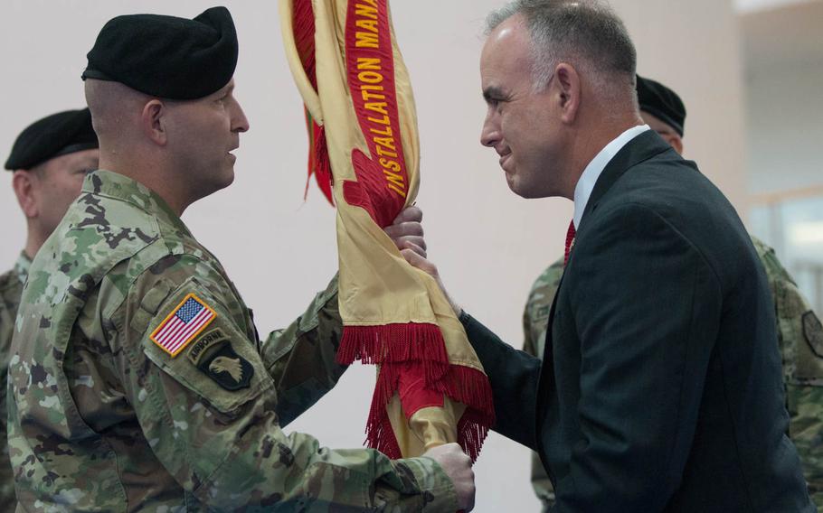 The interim commander of U.S. Army Garrison Bavaria, Col. William E. Rieper, receives the guidon from Michael Formica, director of Installation Management Command-Europe, during a relinquishment of command ceremony in Grafenwoehr, Germany, on Friday, June 3, 2016.