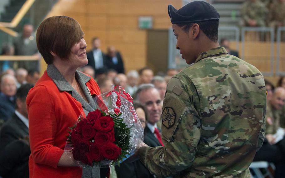Spc. Leanna Buford hands a bouquet of roses to Kelly Colbrook, wife of Col. Mark Colbrook, the outgoing commander of U.S. Army Garrison Bavaria during a command relinquishment ceremony in Grafenwoehr, Germany, on Friday, June 3, 2016.