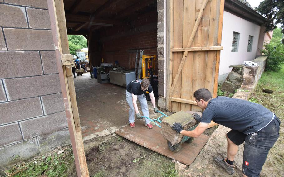 Pfc. Thomas Laroche of 5th Detachment, 603rd Aviation Support Battalion, 12th Combat Aviation Brigade, left, assists a resident in the cleanup of a flood-damaged home in Markt Obernzenn, Germany, on Wednesday, June 1, 2016. The town suffered heavy flooding and reached out to the nearby U.S. garrison in Ansbach for assistance.