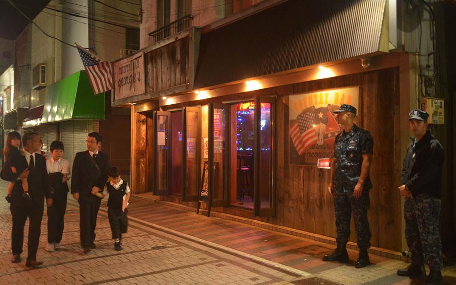 Michael Nelson, second from right, a Navy petty officer second class who works as an intelligence specialist with the 7th Fleet out of Yokosuka Naval Base, Japan, and Devon Hays, right, a petty officer second class assigned to the USS Blue Ridge, patrol Honch, a drinking district outside the base popular with servicemembers, Monday, June 6, 2016. Sailors in Japan are barred until further notice from nonessential off-base activities and banned from drinking alcohol, Navy officials announced Monday.