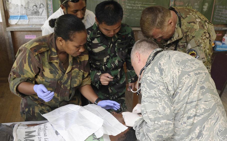 Air Force Lt. Col. Jeffrey Freeland, bottom right, removes a fatty tumor from a local man's head while medical professionals from Papua New Guinea, Indonesia and the U.S. Air National Guard assist during Pacific Angel 2015 at Unggai Primary School in Papua New Guinea, June 1, 2015. This year's Pacific Angel is underway in Cambodia through June 18.
