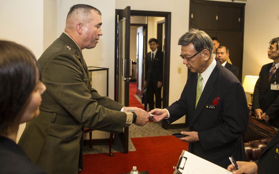 Lt. Gen. John Wissler, former Okinawa area coordinator for U.S. Forces Japan, hands his business card to Okinawa Gov. Takeshi Onaga, shortly after his election, Dec. 18, 2014, at Camp Foster. Calling the  prefectural election on Sunday, June 5, 2016, a landslide victory, Onaga expressed confidence in his anti-military stance.