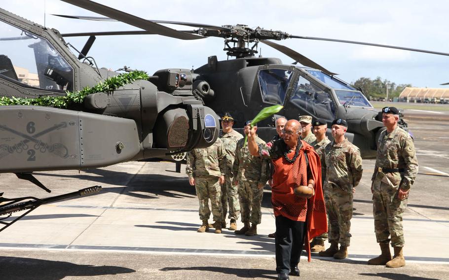 Shad Kane waves ti leaves around an Apache helicopter as a Hawaiian blessing during a ceremony at Wheeler Army Airfield. Hawaii, Thursday, June 9, 2016. The 25th Combat Aviation Brigade welcomed 24 Apaches into the fold at the ceremony.