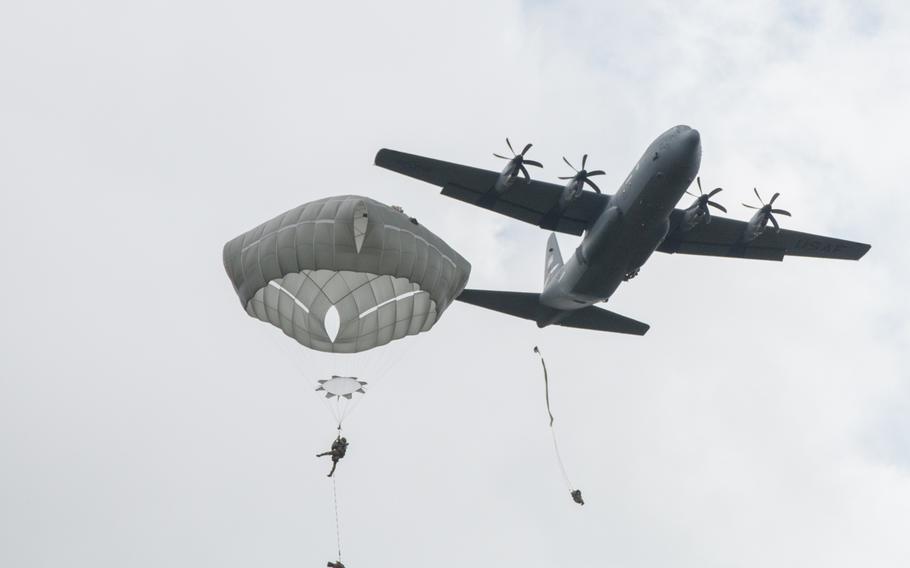 An American C-130 passes by a soldier drifting to earth during an air assault on the Hohenfels, Germany, training area on Wednesday, June 15, 2016.