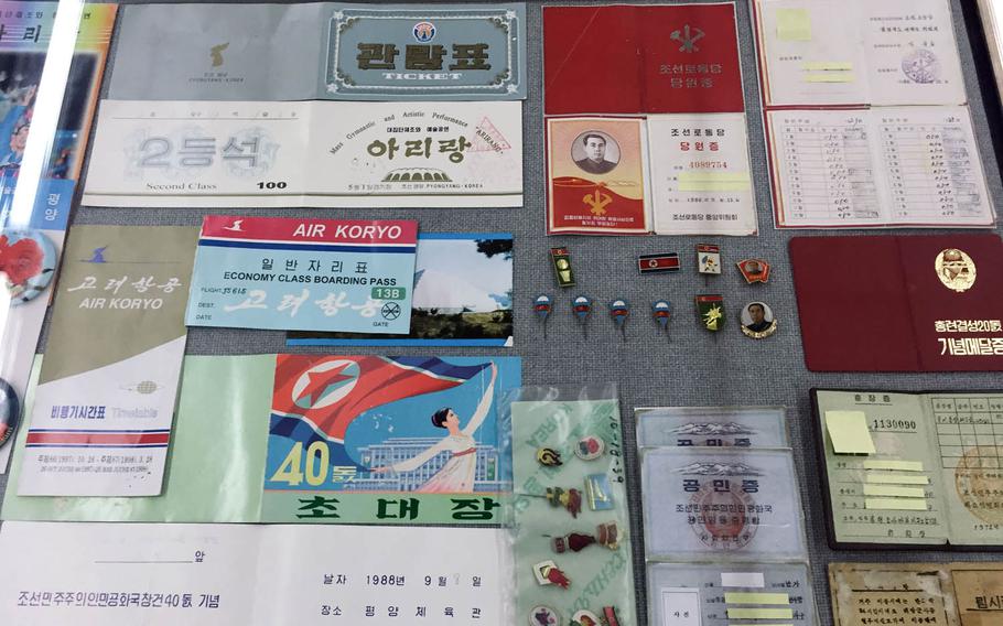 A display case at the North Korea Information Center in Seoul, South Korea, holds tickets for North Korea's national airline and cultural events, along with lapel pins bearing the image of the communist country's founder Kim Il Sung and official documents with identifying information blocked out.