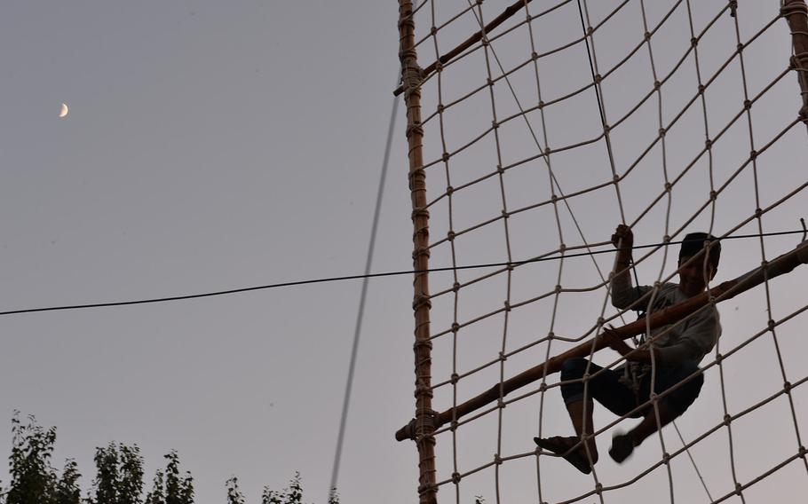 As night falls, Afghan scouts climb a 30-foot wall of rope netting well in Kabul on Sept. 8, 2016, before breaking for dinner. The scouts were participating in a three-day camping event, where they learned outdoor skills, environmental responsibility and tools for building peace.