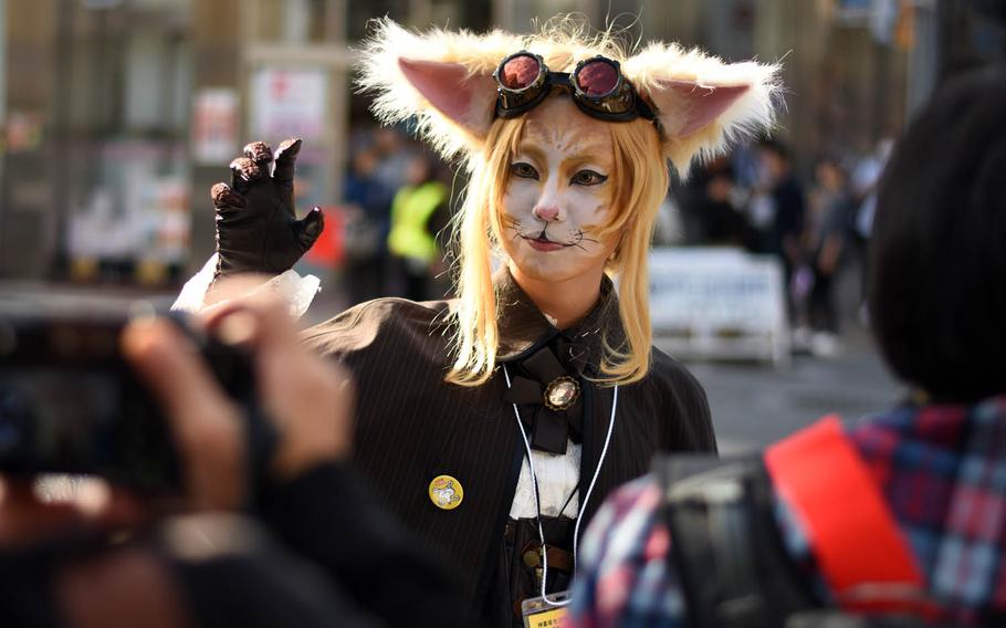 A woman poses for photographers during the Bakeneko festival, Sunday, Oct. 16, 2016, in Tokyo. The annual Halloween-like festival, whose name roughly translates to "ghost cat with supernatural powers," includes a long and lively parade of costumed revelers, live music and street dancing.