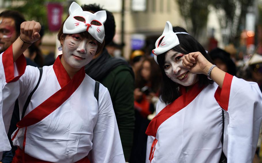 Women pose for photographers during the Bakeneko festival, Sunday, Oct. 16, 2016, in Tokyo. The annual Halloween-like festival includes a long and lively parade of costumed revelers, live music and street dancing.