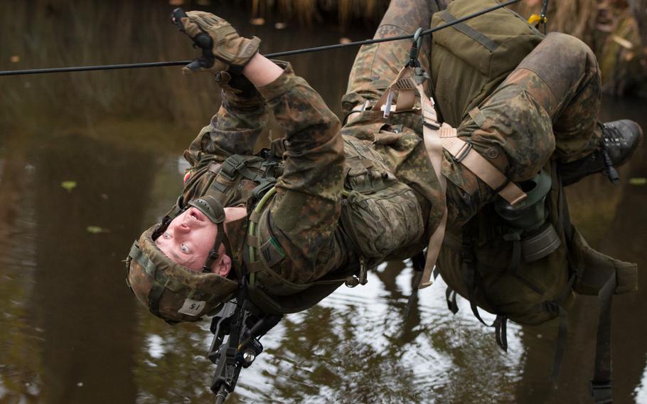 German Pfc. Vitali Krell dangles from a rope as he crosses an ice-cold river during the final day of the 2015 European Best Squad Competition at the Grafenwoehr, Germany, Training Area, Oct. 19-22, 2015. The Germans beat out 16 other squads to earn the title of Best Squad in Europe. German Chancellor Angela Merkel has said Germany must drastically increase its defense spending.
