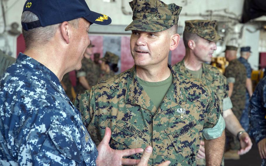 Maj. Gen. Russell Sanborn, right, 1st Marine Aircraft Wing commander, speaks with Capt. Jeffrey Ward, left, commanding officer of the amphibious assault ship USS Bonhomme Richard, Aug. 20, 2016. Sanborn draws on his experiences as a captive during Operation Desert Storm when training other servicemembers.