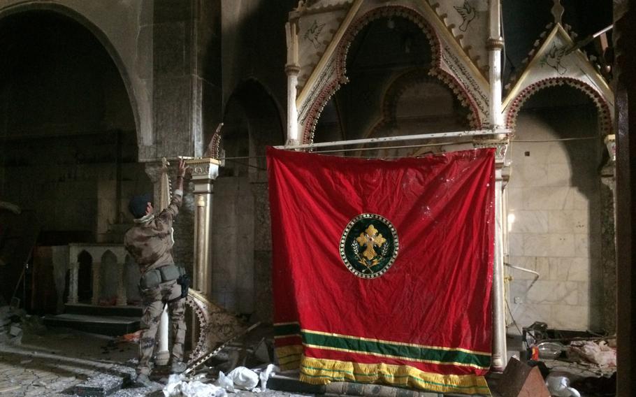 A member of the Golden Division tidies up inside a damaged church in Bartella, a Christian Village east of Mosul, Wednesday, Oct. 26, 2016.