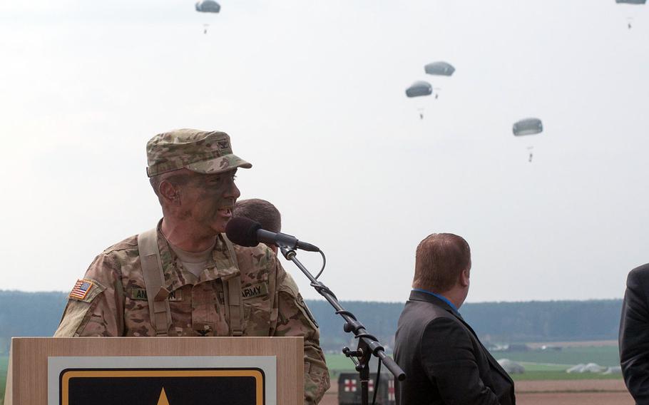U.S. Army Col. Greg Anderson, the 173rd Airborne Brigade commander, speaks to a gathered crowd as some of his men continue to drop in behind him as part of the U.S. Army Europe-led Saber Junction 16 exercise. Anderson was one of the first soldiers out of the airplane as they soared over the Hoechensee, Germany, countryside as part of an air assault, Tuesday, April 12, 2016.