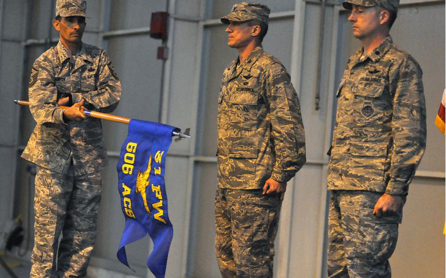 Master Sgt. Andrew Horton unfurls a guidon during the activation ceremony of the 606th Air Control Squadron at Aviano Air Base, Italy, on Tuesday, Nov. 1, 2016. Col. Craig Hollis, center, 31st Operations Group commander, and Lt. Col. Aaron Gibney, the 606th commander, stand at attention.
