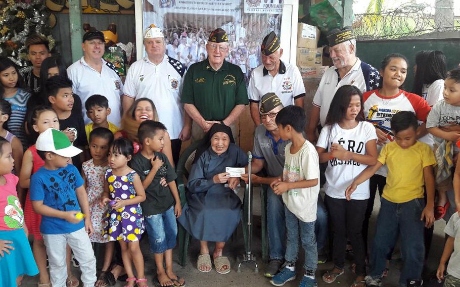 Members of Veterans of Foreign Wars Post 2485 in Angeles City, Philippines, pose with sister Alessandria Casas and orphans at Duyan Ni Maria Children's Home after donating $5,000 to the orphanage near Clark Air Base.