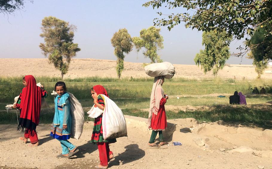 Afghan girls carry their belongings on Thursday,  Oct. 6, 2016, outside the Samarkhel Encashment Center near Jalalabad in eastern Afghanistan, where thousands of Afghan refugees returning from Pakistan are registered and given cash and other assistance.