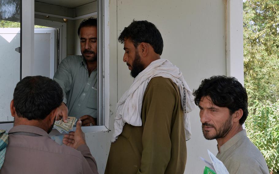 A worker at the Samarkhel Encashment Center outside Jalalabad, Afghanistan, on Thursday, Oct. 6, 2016, distributes cash to Afghan men returning from years of seeking refuge in Pakistan. Families receive about $400 per member to help pay the costs of resettling in their homeland.