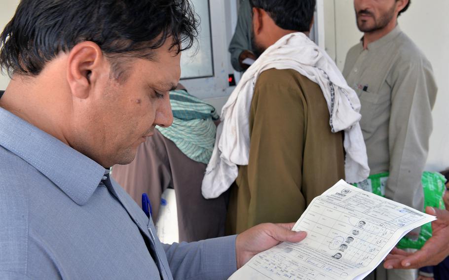 Abdul Wali, director of the Samarkhel Encashment Center outside Jalalabad, Afghanistan, looks over registration documents for a family of 10 refugees returning from Pakistan on Thursday, Oct. 6, 2016.