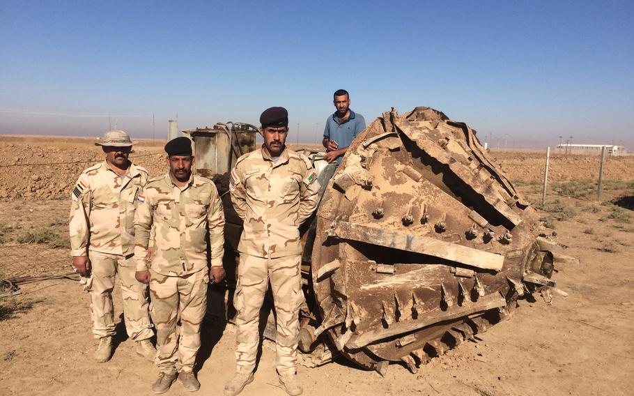 Iraqi soldiers pose on Wednesday, Nov. 2, 2016, alongside a mining machine they captured from the Islamic State group near the village of Kermlis, east of Mosul.