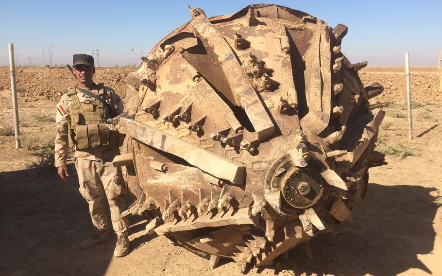 An Iraqi soldier poses, on Wednesday, Nov. 2, 2016, with a mining machine captured from the Islamic State group near Kermlis, east of the city of Mosul.
