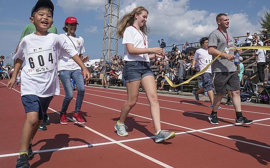 Athletes and their buddies cross the finish line of the 50-meter dash at the 2016 Kadena Special Olympics.