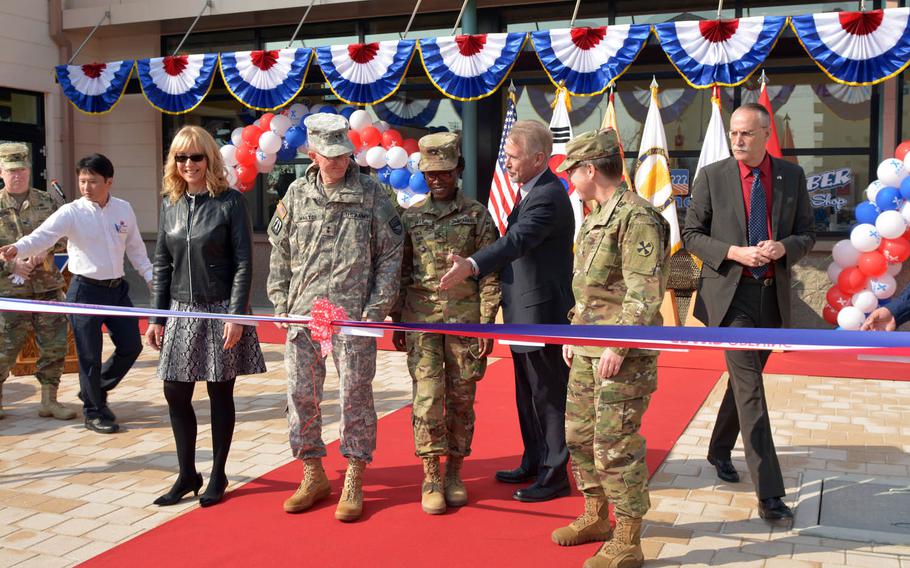 Karin Duncan, left, the Army and Air Force Exchange Service's senior vice president of the overseas region, and Maj. Gen. James Walton, director of transformation and restationing for U.S. Forces Korea, to Duncan's right, and other officials prepare to cut the ribbon to mark the opening of a new troop minimall, Tuesday, Nov. 8, 2016. The $6.2 million facility is part of a massive expansion of Camp Humphreys as the military relocates most of its forces south of Seoul in coming years.
