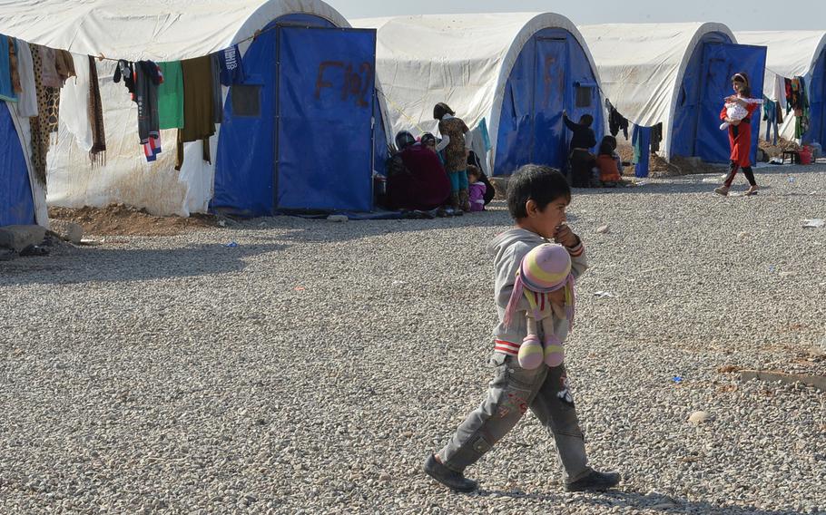 A boy at the Khazir displacement camp, about 20 miles from Mosul, Iraq, carries a stuffed toy through the camp where about 1,300 families were living on Monday, Nov. 7, 2016.