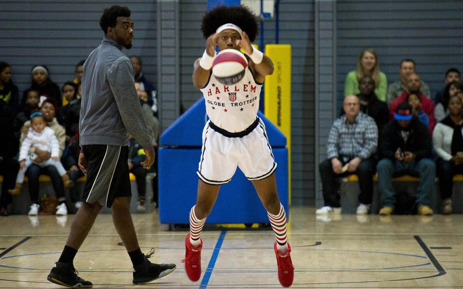 Harlem Globetrotter Moose Weekes, right, takes a shot to warm up before a game at Ramstein Air Base, Germany, on Thursday, Nov. 10, 2016.