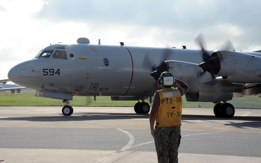 Petty Officer 3rd Class Ralph Topps from the Golden Swordsmen of Patrol Squadron 47 salutes the pilot as a P-3C Orion begins to taxi to the runway in late October at Kadena Air Base, Japan.