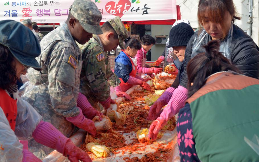 South Koreans teach U.S. soldiers with the 210th Field Artillery Brigade how to make kimchi, Thursday, Nov. 17, 2016, at a volunteer center in Dongducheon, South Korea. The traditional fermented dish, made of vegetables and seasonings, will be donated to elderly people who live alone in the area.