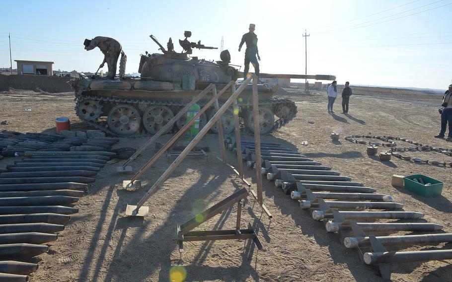 Iraqi soldiers climb on a Soviet-made T-55 tank, which was seized from Islamic State fighters in the village of Ali Rash outside Mosul and was on display with other seized hardware and munitions near the Iraqi army's 9th armored division's camp in Karamlis on Saturday, Nov. 19, 2016.