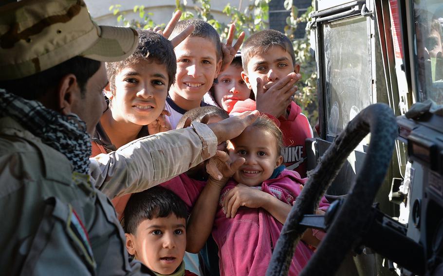 An Iraqi army Humvee driver pats the top of a young girl's head as children gather at the door of his vehicle in the Intisar neighborhood of Mosul on Saturday, Nov. 19, 2016. The residents of the area said food and water had been scarce during the two years Islamic State fighters occupied it before it was liberated as pat of a campaign to drive the militants out of their last major urban stronghold in Iraq's second-largest city.