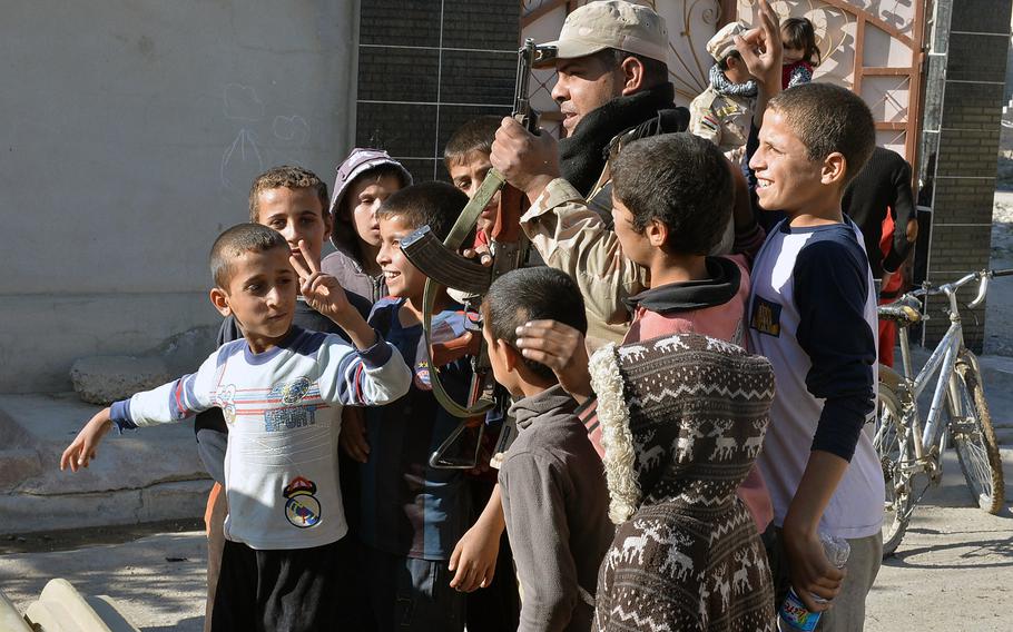 Children pose for a photo with an Iraqi soldier in the Intisar neighborhood of Mosul on Saturday, Nov. 19, 2016. Soldiers with the Iraqi army's 9th Armored Division liberated the city from Islamic State group control as part of a campaign to retake Mosul from the militants.