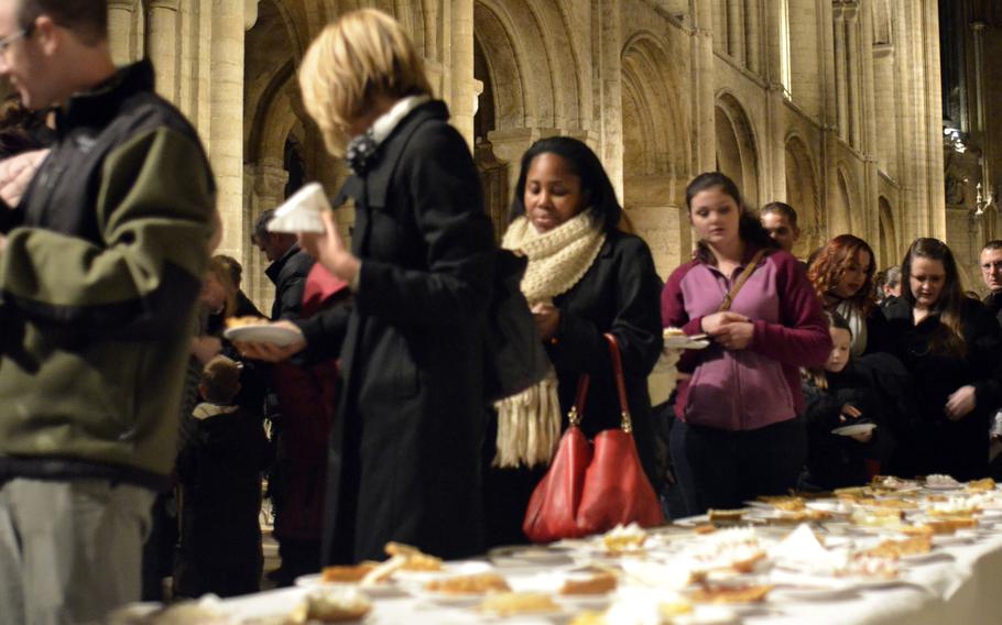 U.S. servicemembers, families and British neighbors enjoy free pie and beverages after a church service on the Eve of Thanksgiving, Wednesday, Nov. 23, 2016, at the historic Ely Cathedral in England.
