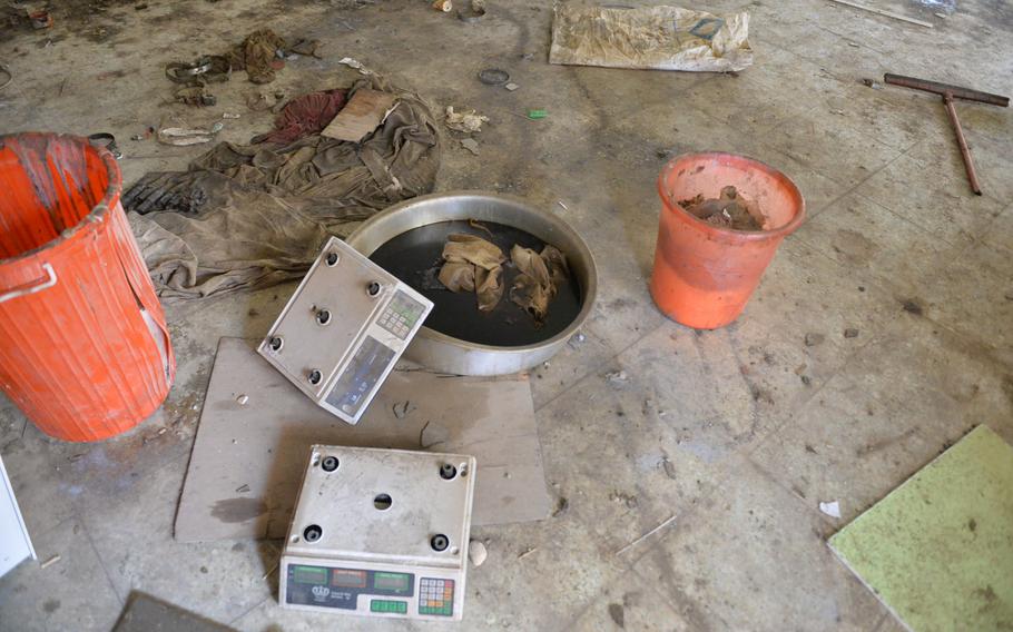 Scales, tubs of chemical precursors for rocket propellant, and a tub of oil, likely for heating the propellant mix, lie on the floor of a building at St. George's Church in Qaraqosh, Iraq, Dec. 17, 2016. The building was the site of an Islamic State weapons workshop.