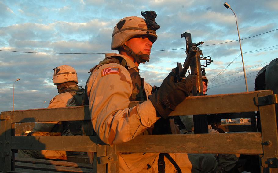 Pfc. Brent Phillips, a mortarman from Hickory Ridge, Ark., sits in the back of a Humvee with an M4 carbine during a morning patrol for roadside bombs in Mosul, Iraq, Nov. 21, 2003.