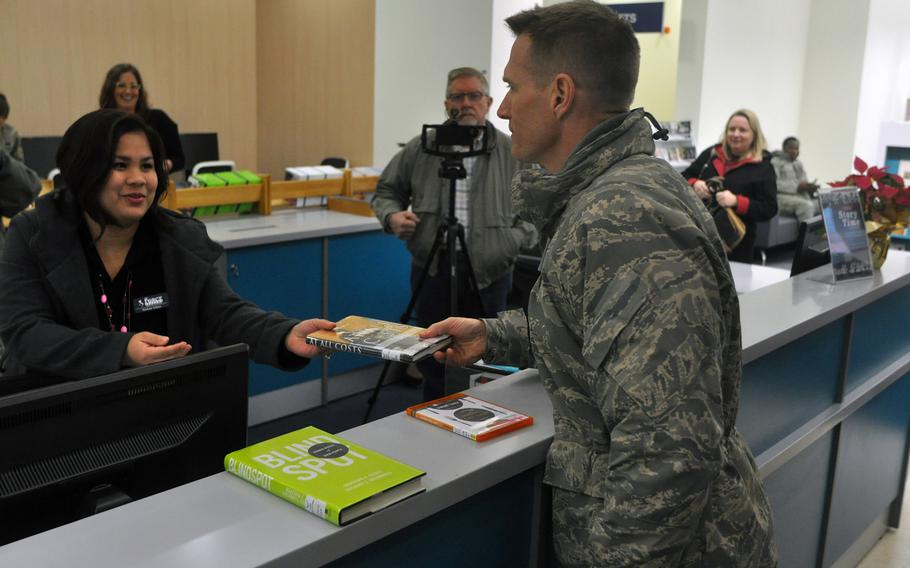 Brig. Gen. Lance Landrum, commander of the 31st Fighter Wing, officially checks out the first book from the new base library at Aviano Air Base, Italy, on Friday, Jan. 6, 2017, with the help of library technician Madona Solana.