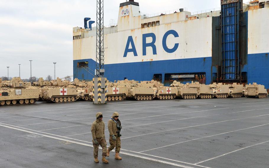 Two soldiers walk past armored vehicles at the port of Bremerhaven, Germany, on Sunday, Jan. 8, 2017. The 3rd Armored Brigade Combat Team, 4th Infantry Division, out of Fort Carson, Col., is headed to Poland for a nine-month rotation as part of Operation Atlantic Resolve.