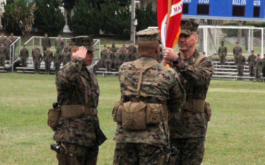 Maj. Gen. Richard Simcock II, right, the outgoing 3rd Marine Division commander, passes the division banner to  Maj. Gen. Craig Timberlake during a change-of-command ceremony at Camp Courtney, Okinawa, Friday, Jan. 20, 2017. Sgt. Maj. Vincent Santiago, left, the division's top enlisted leader, salutes.