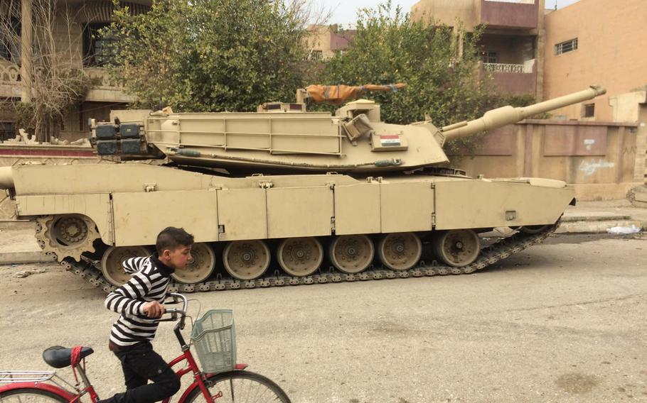 A boy bikes past a tank in Mosul, Iraq, on Saturday, Jan. 21, 2017. 