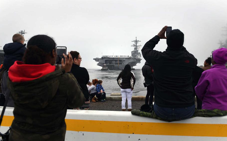 Family members and friends take pictures from the pier as aircraft carrier USS George H.W. Bush departs Naval Station Norfolk, Va., for a deployment to the 5th and 6th Fleet areas of operation, Saturday Jan. 21, 2017. 