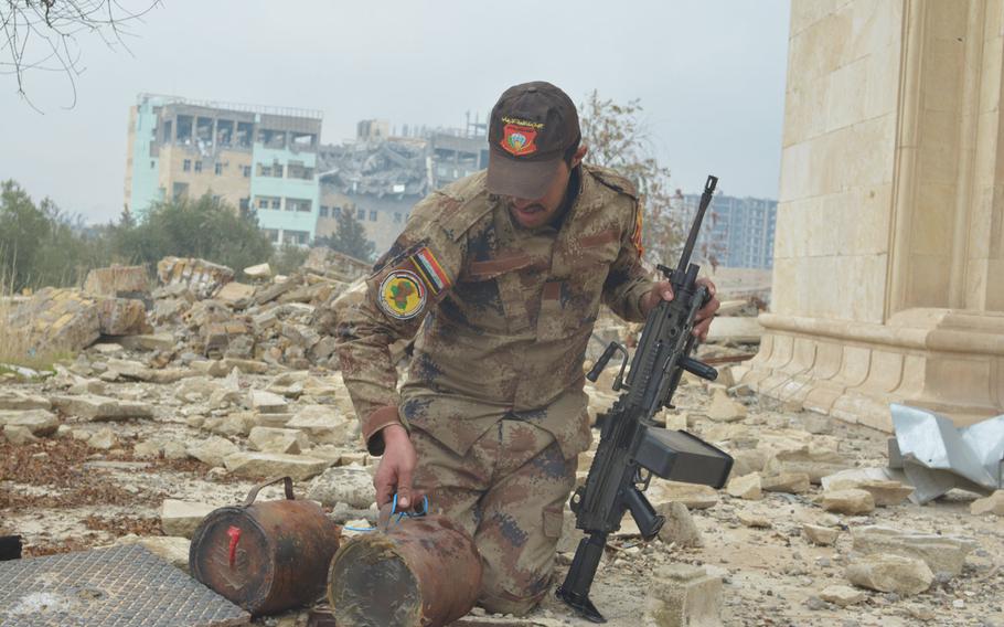 A soldier pulls improvised explosive devices out of a hole beside a palace overlooking the Tigris River in Mosul, Iraq, on Wednesday, Jan. 25, 2017.